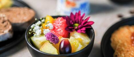 Un tazón de ensalada de frutas con diversas frutas y flores.