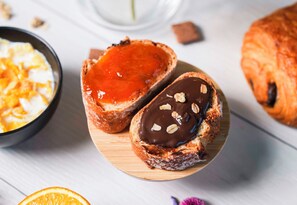 Twee gebakjes op een houten plank, één met rode confituurvulling en de andere met chocolade en noten.