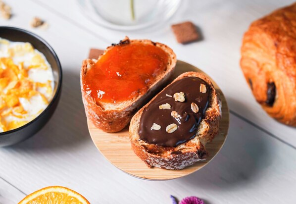 Deux pâtisseries sur une planche en bois, l’une fourrée à la confiture de fruits rouges et l’autre au chocolat et aux noix.
