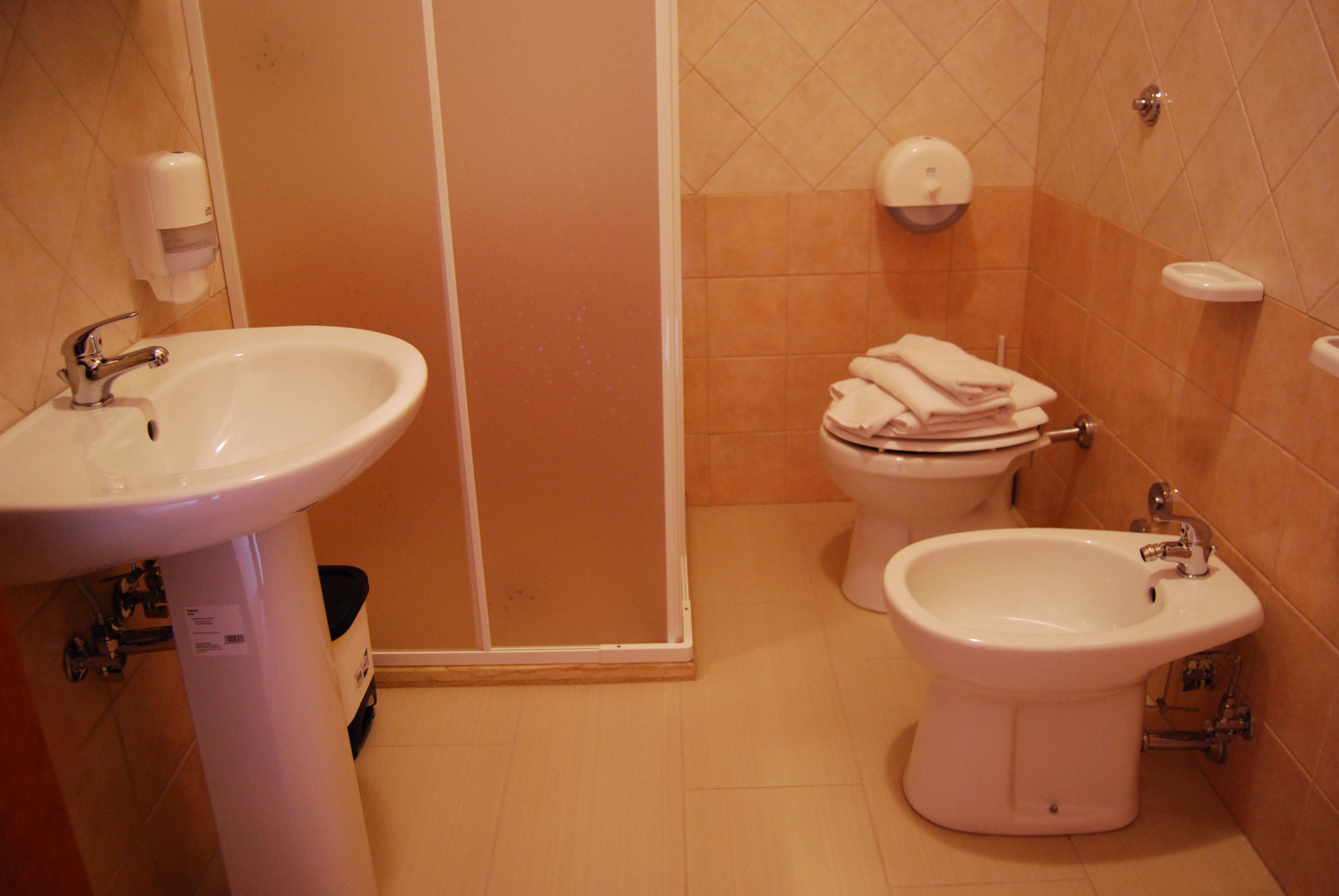Une salle de bain équipée d’un lavabo, d’un bidet, de toilettes et d’un porte-serviettes.