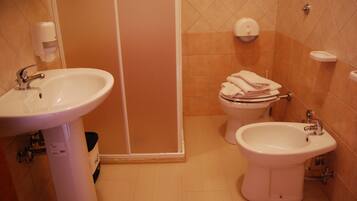 A bathroom with a sink, bidet, toilet, and a towel rack.