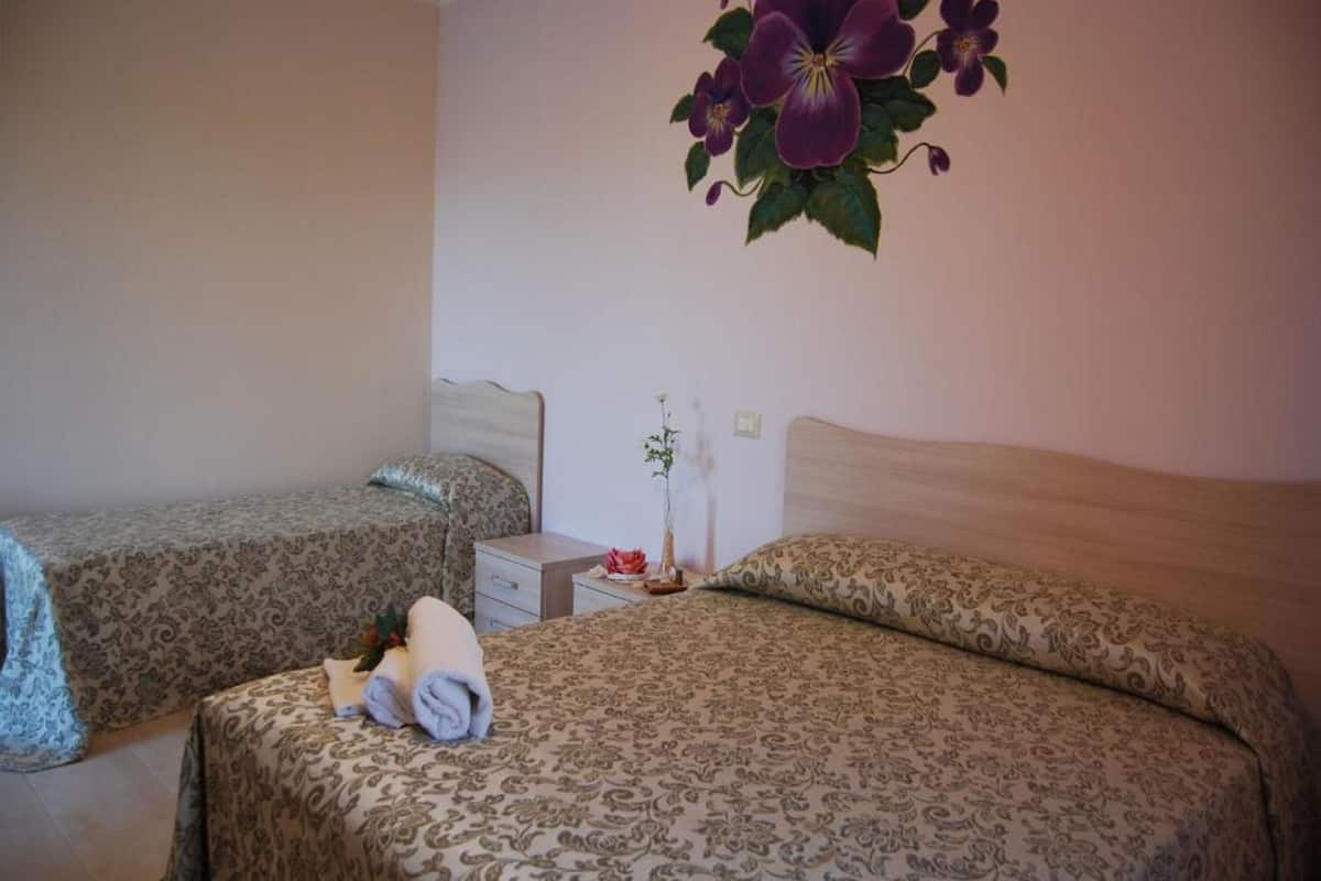 Une chambre d’hôtel avec deux lits, une table de chevet et une décoration florale fixée au mur.