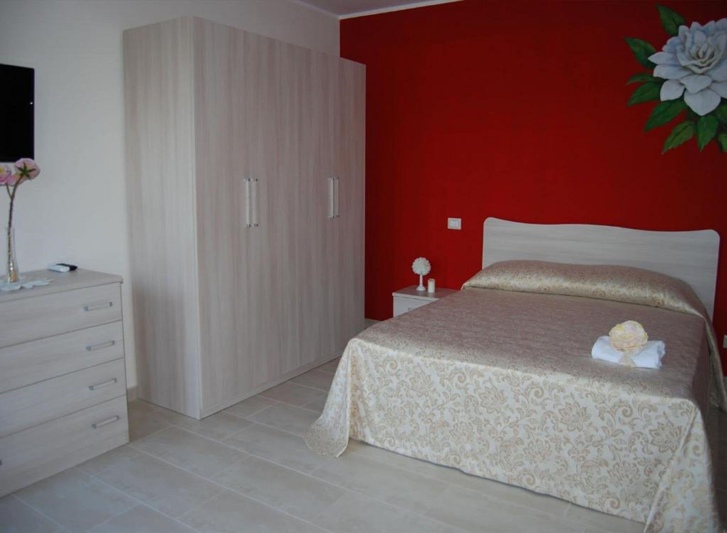 A bedroom with a bed, a dresser, and a wardrobe.