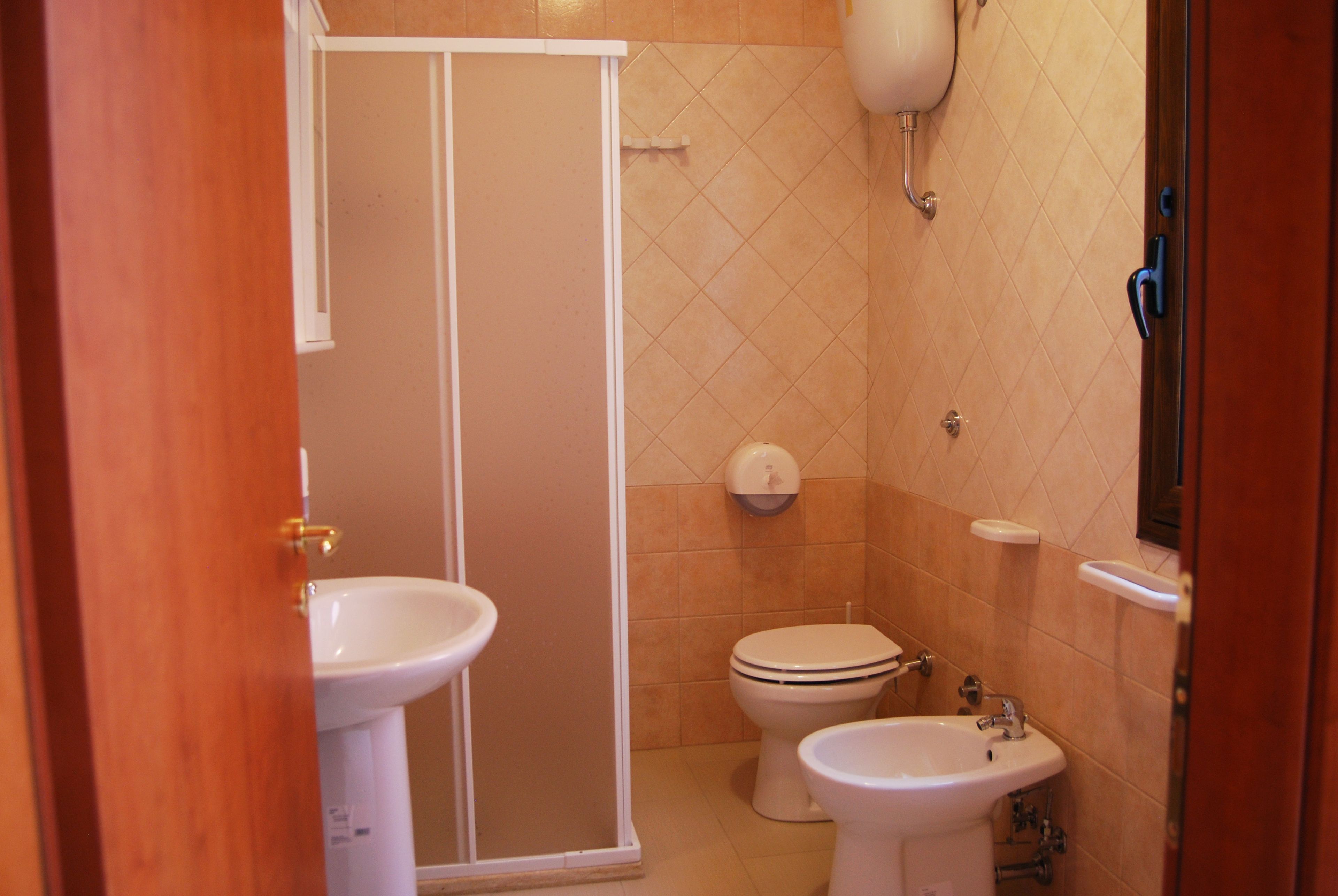 A bathroom with a shower, toilet, and two sinks.