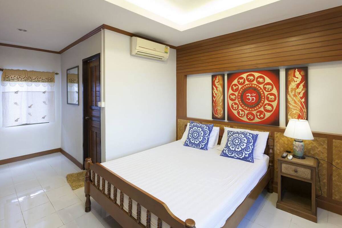 A hotel room with a wooden bed, a nightstand with a lamp, and decorative wall art.