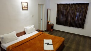Une chambre d’hôtel avec un lit, une table de chevet, un miroir et une fenêtre avec des rideaux.