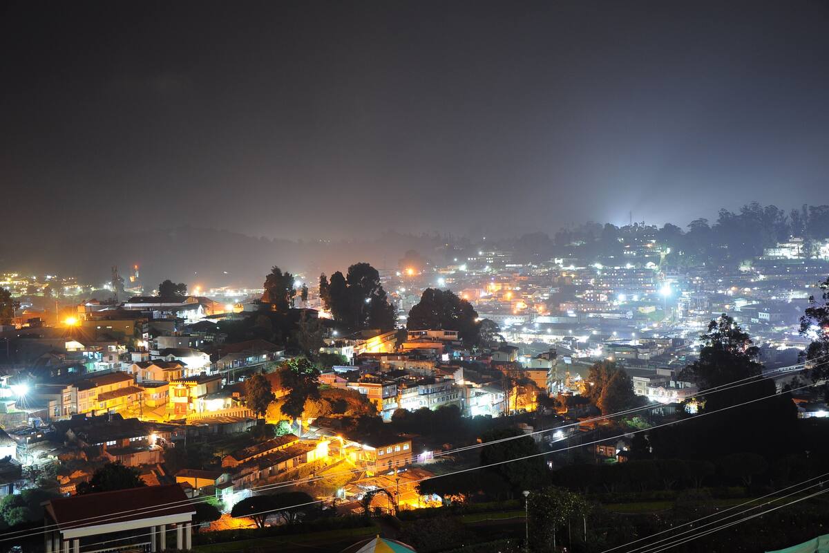 A nighttime cityscape with illuminated buildings and a hazy atmosphere.