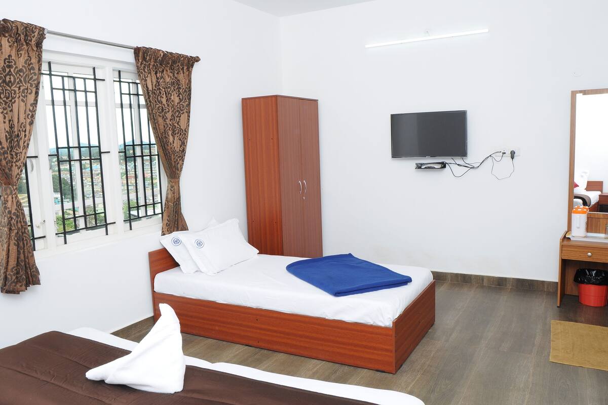 A hotel room with a bed, wardrobe, TV, and a small desk with a mirror.