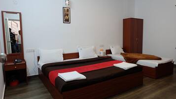 Quarto de hotel com cama grande, guarda-roupa, mesa de cabeceira e espelho.