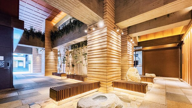 A modern lobby with a stone floor, wooden benches, and a large rock centerpiece. - Hotel Hillarys Akasaka (Tokyo)