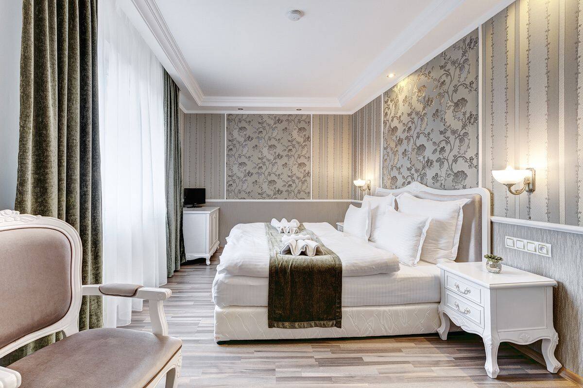 Un dormitorio ordenado con una cama grande, mesitas de noche y una silla.