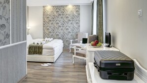 Quarto de hotel com cama, escrivaninha com computador, televisão e mala.