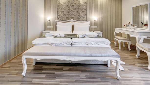 Um quarto espaçoso com uma cama grande, uma toucador com espelho e uma mesa de cabeceira.