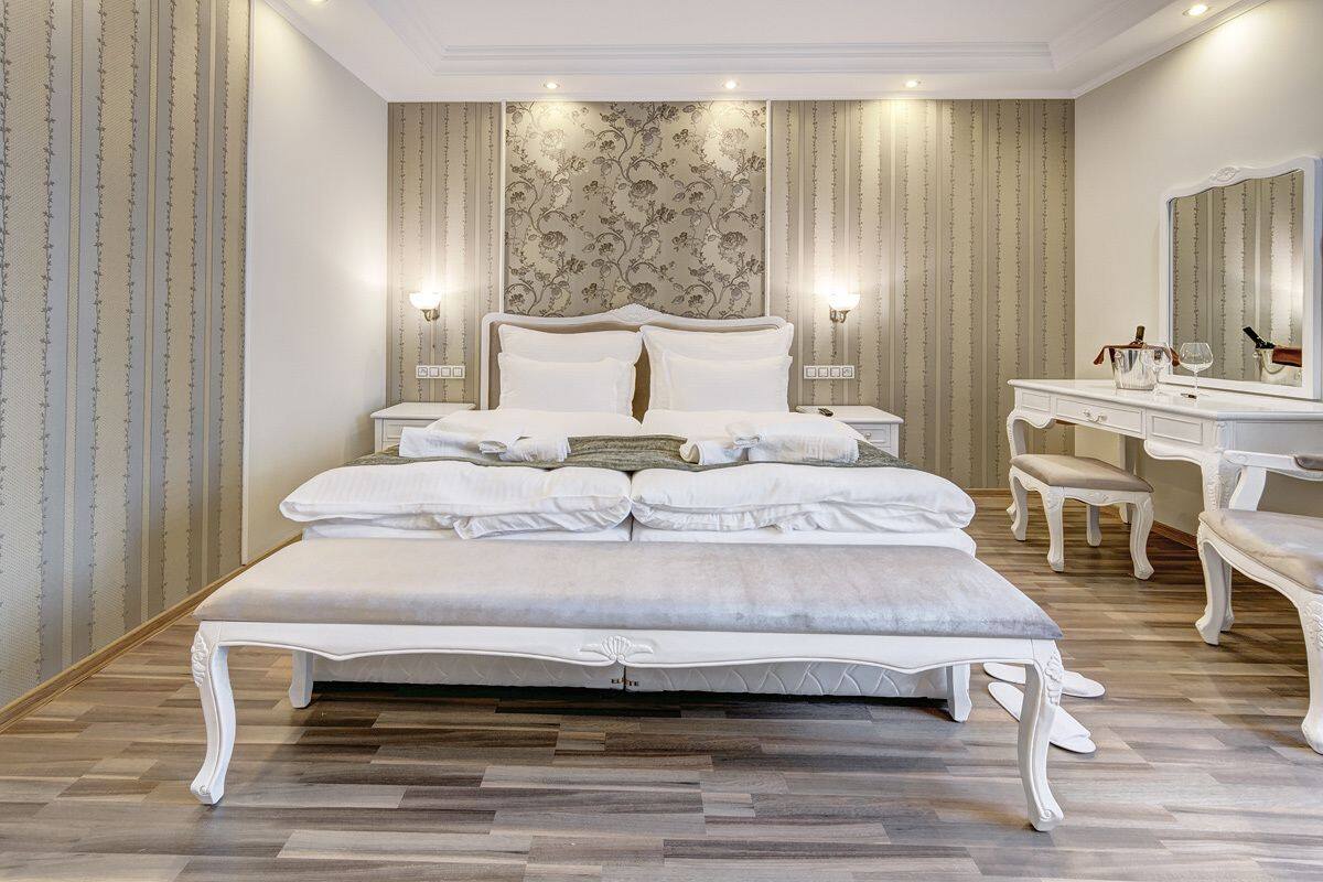 Un dormitorio espacioso con una cama grande, un tocador con espejo y una mesita de noche.