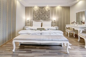 Un dormitorio espacioso con una cama grande, un tocador con espejo y una mesita de noche.