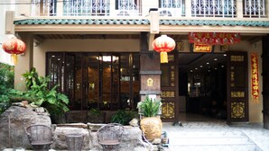 A traditional building with a tiled roof, wooden doors, and a balcony with metal railings. - Minatale Phuket (Patong)