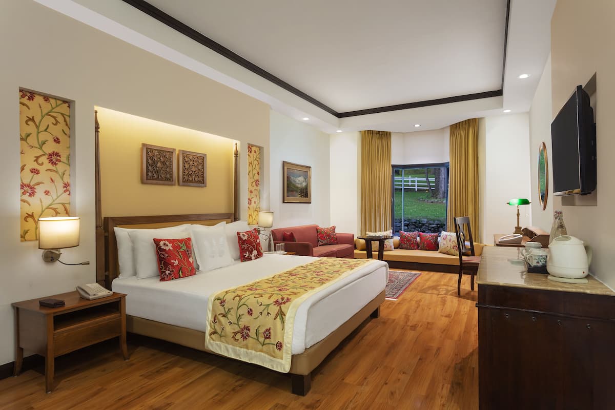 A hotel room with a large bed, a sofa, a desk, and a TV.