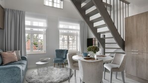 Un salon moderne avec un escalier, un coin repas doté d’une table ronde et un canapé agrémenté d’un tapis moelleux.
