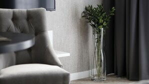 Une pièce moderne avec un fauteuil à capitons, un vase transparent contenant des plantes vertes et un design minimaliste.