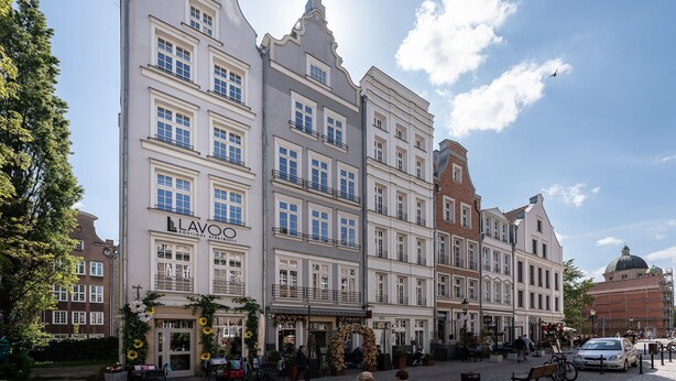 Un bâtiment historique à étages, une enseigne « LAVOO » bien visible et une rue pavée.
