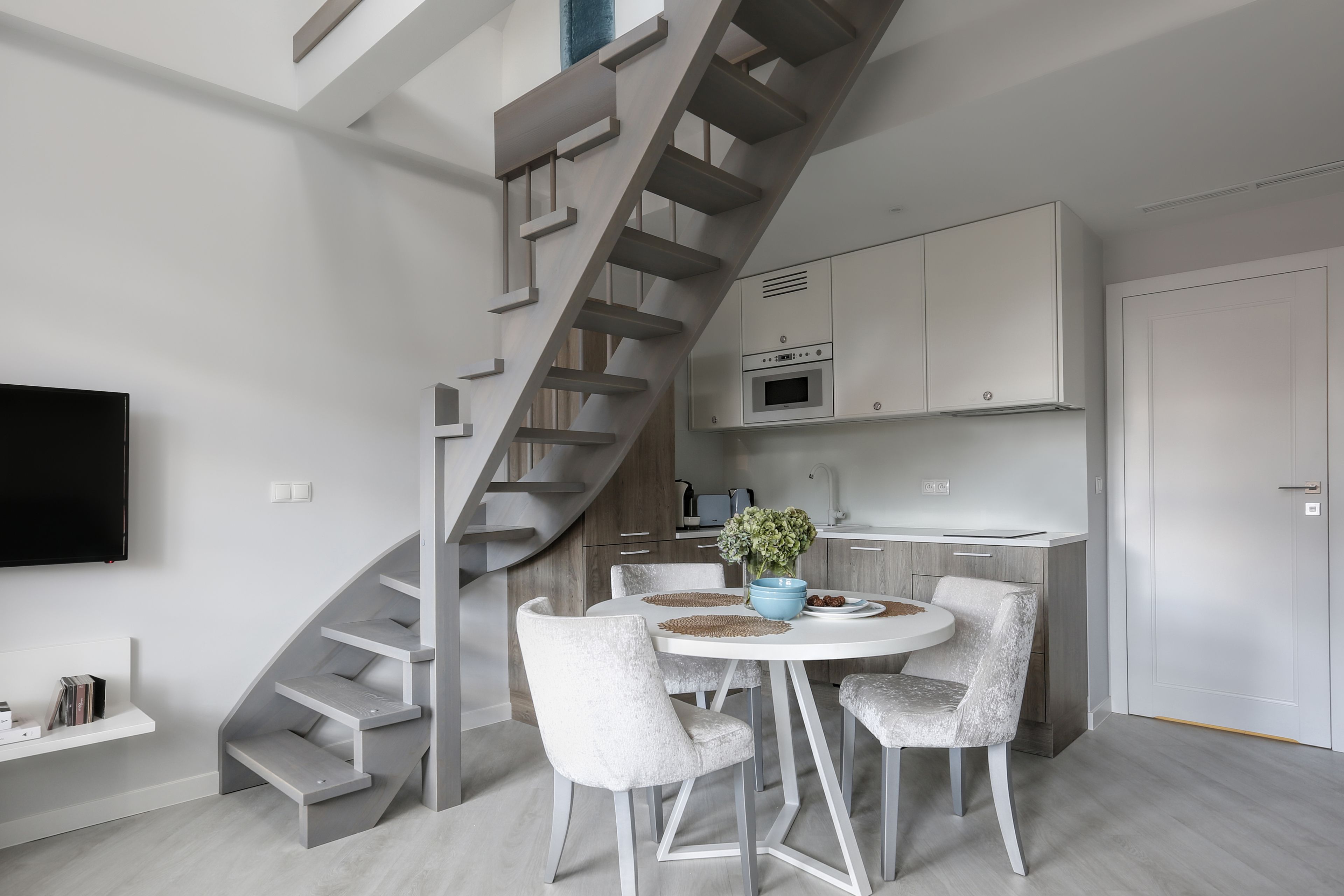 Une cuisine moderne dotée d’un îlot central, de meubles blancs et d’un four encastré.