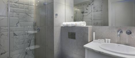 A modern bathroom with a glass-enclosed shower, a white toilet, and a vanity with a sink and mirror.