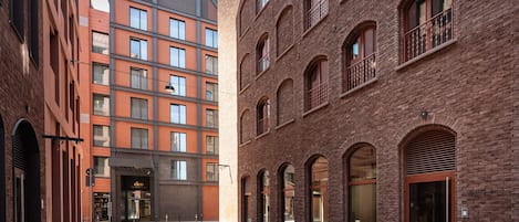 A narrow urban street with a modern building featuring large windows and a brick facade.