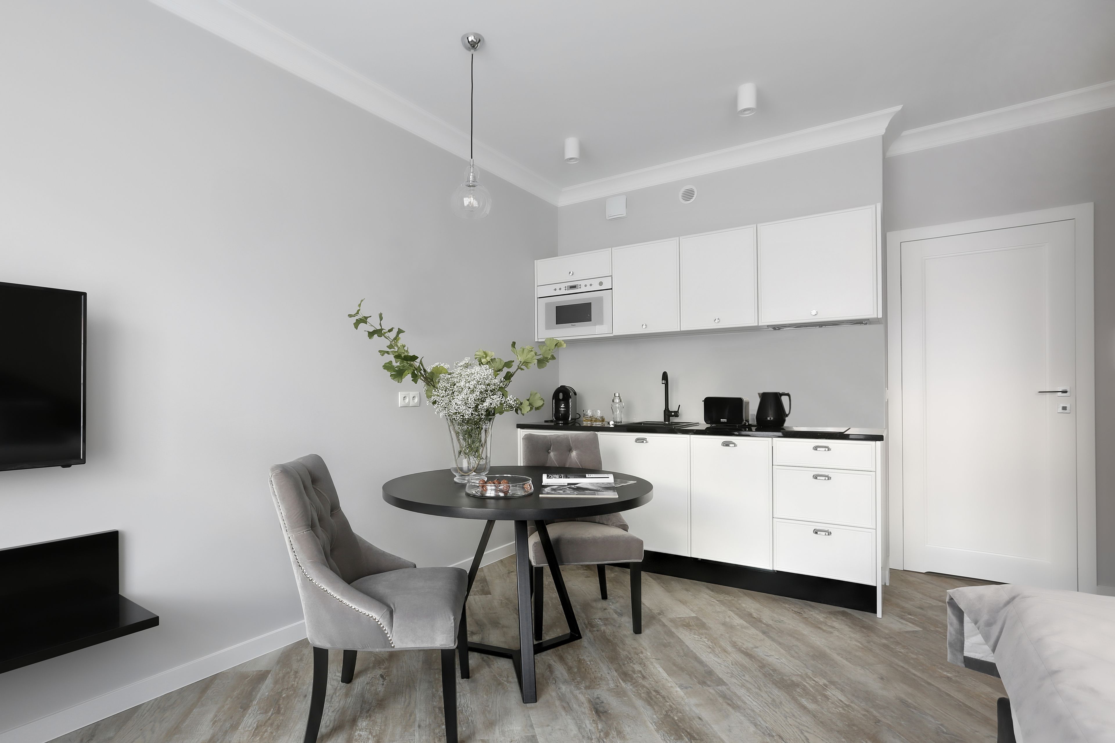 Una sala de estar moderna y minimalista con comedor, cocina y televisor.