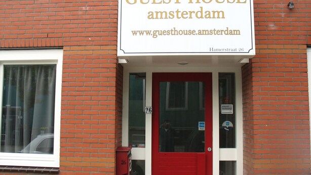 A brick building with a red door and a sign that reads "GUEST HOUSE amsterdam". - Guest House Amsterdam - Hostel (Amsterdam)