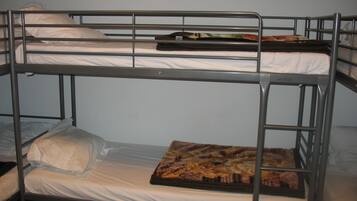 Een stapelbed met matras en kussens.