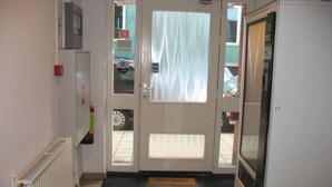 A hallway with a door leading to a garage, a radiator, and a doormat. - Guest House Amsterdam - Hostel (Amsterdam)