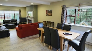 A dining area with a wooden table and chairs, a red sofa, and a fireplace.