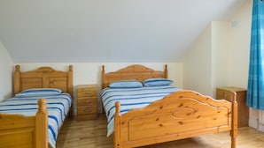 A bedroom with two wooden beds, a nightstand, and a dresser.