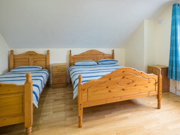 A bedroom with two wooden beds, a nightstand, and a dresser.