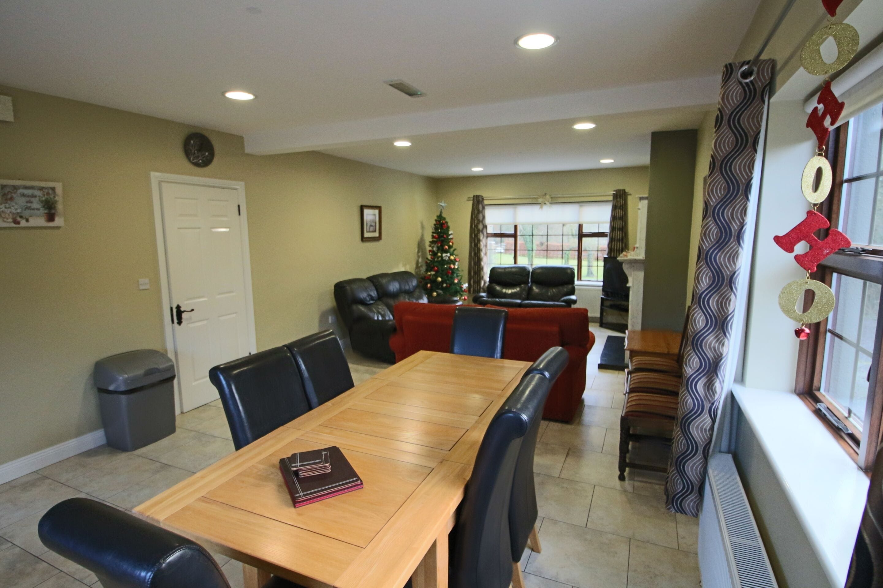 A dining area with a wooden table and chairs, a Christmas tree, and a fireplace.