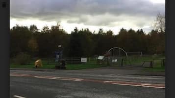 A road with a pedestrian crossing and a fenced area with a playground.