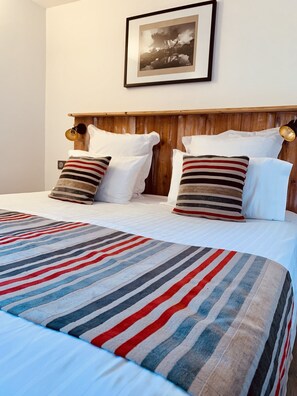 A neatly made bed with striped bedding, a wooden headboard, and a framed picture on the wall. - Auberge Quintessence (Roubion)