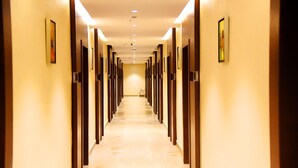 A hotel hallway with a long corridor, doors on both sides, and framed pictures on the walls. - Vybrant Hotels (Vijayawada)