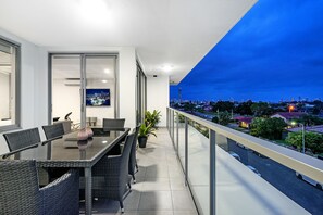 A balcony with a dining area, a city view, and a glass door leading to an indoor space.