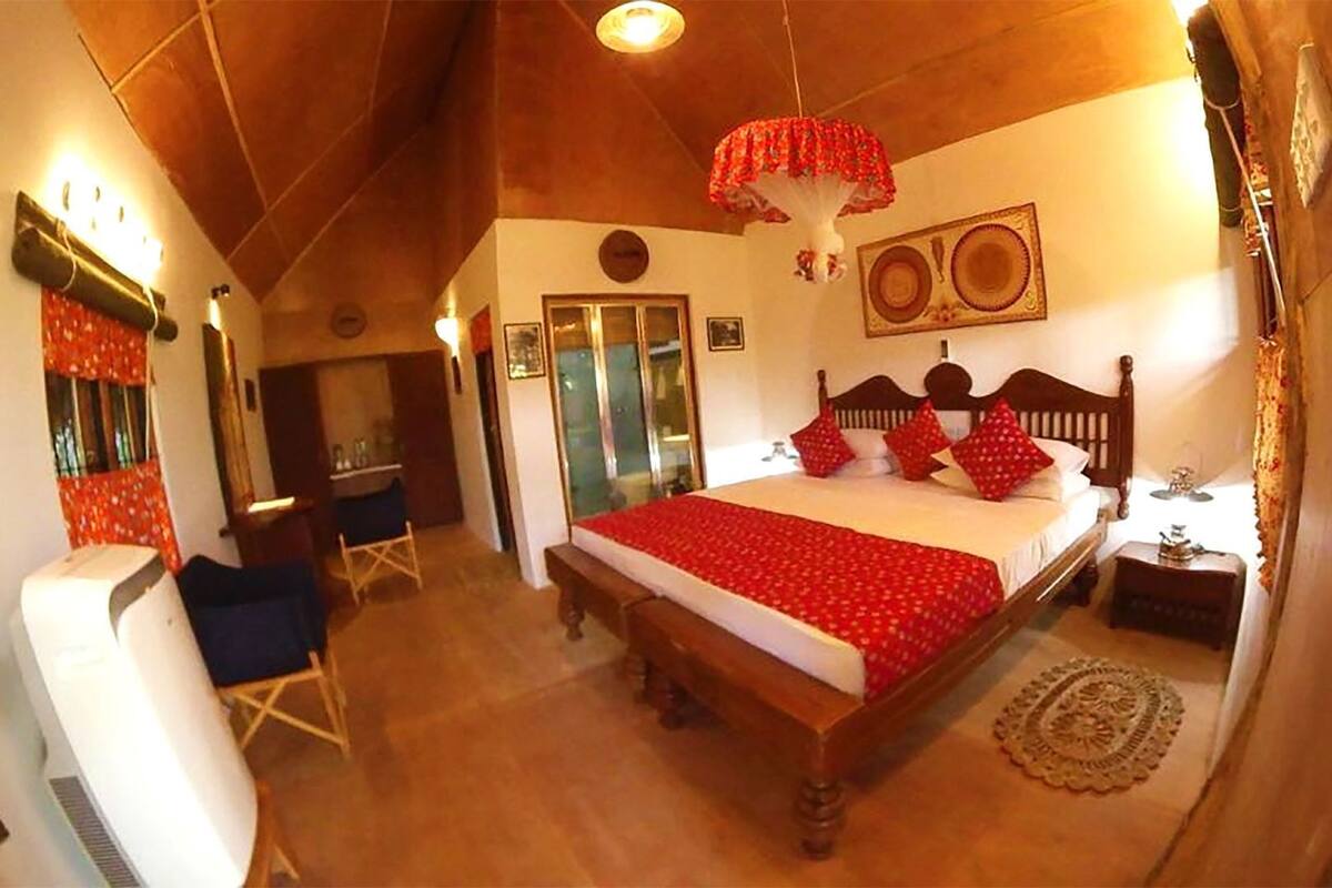 Een slaapkamer met een houten bed, een stoel, een nachtkastje en een plafondventilator.