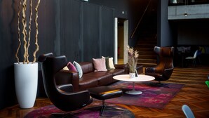 A modern lounge area with a leather sofa, a round table, and a large potted plant. - Roomreich (Ingolstadt)