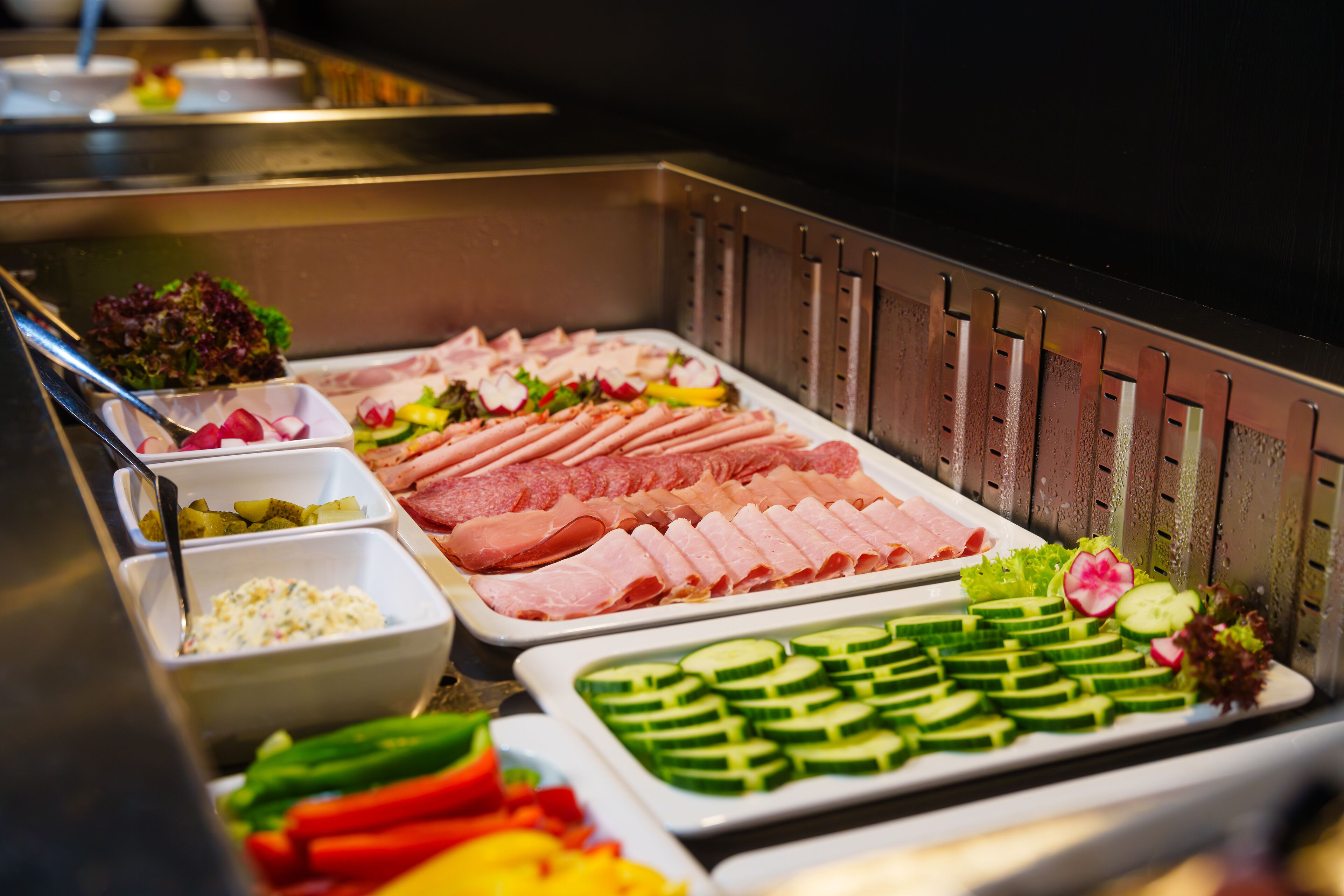A buffet with various food options including meats, vegetables, and salads.