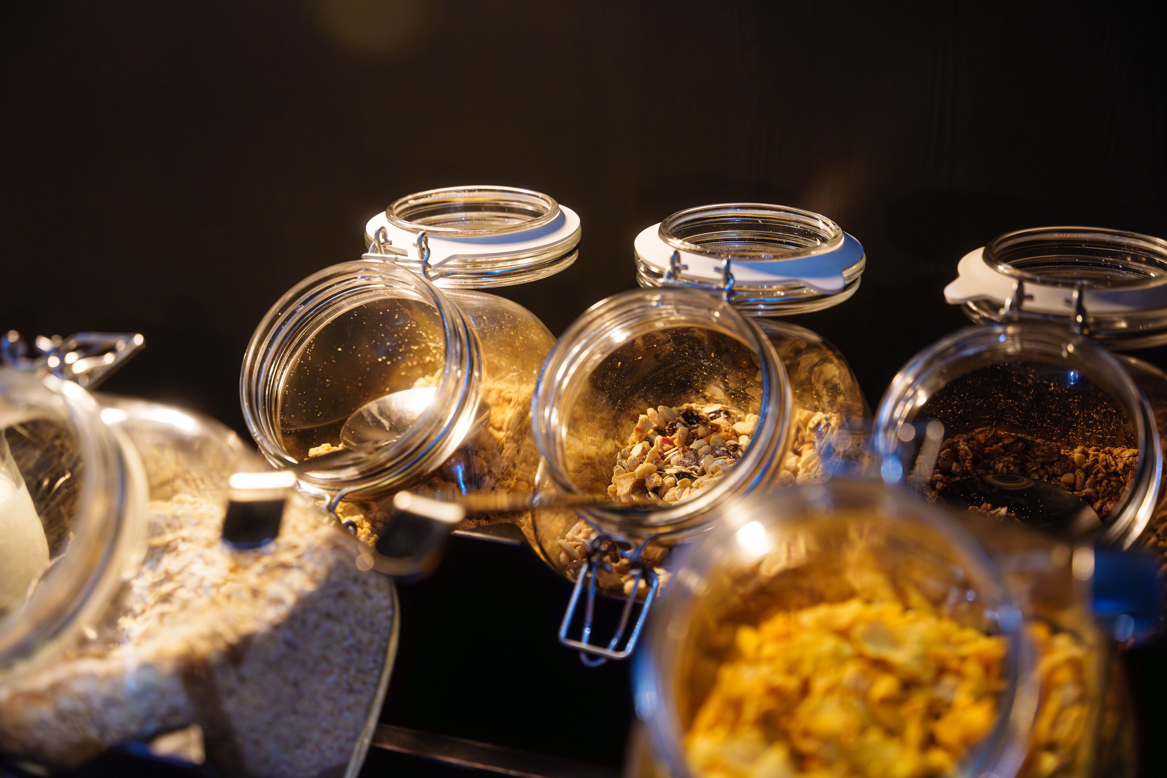 A close-up of several glass jars with metal lids, containing various food items.