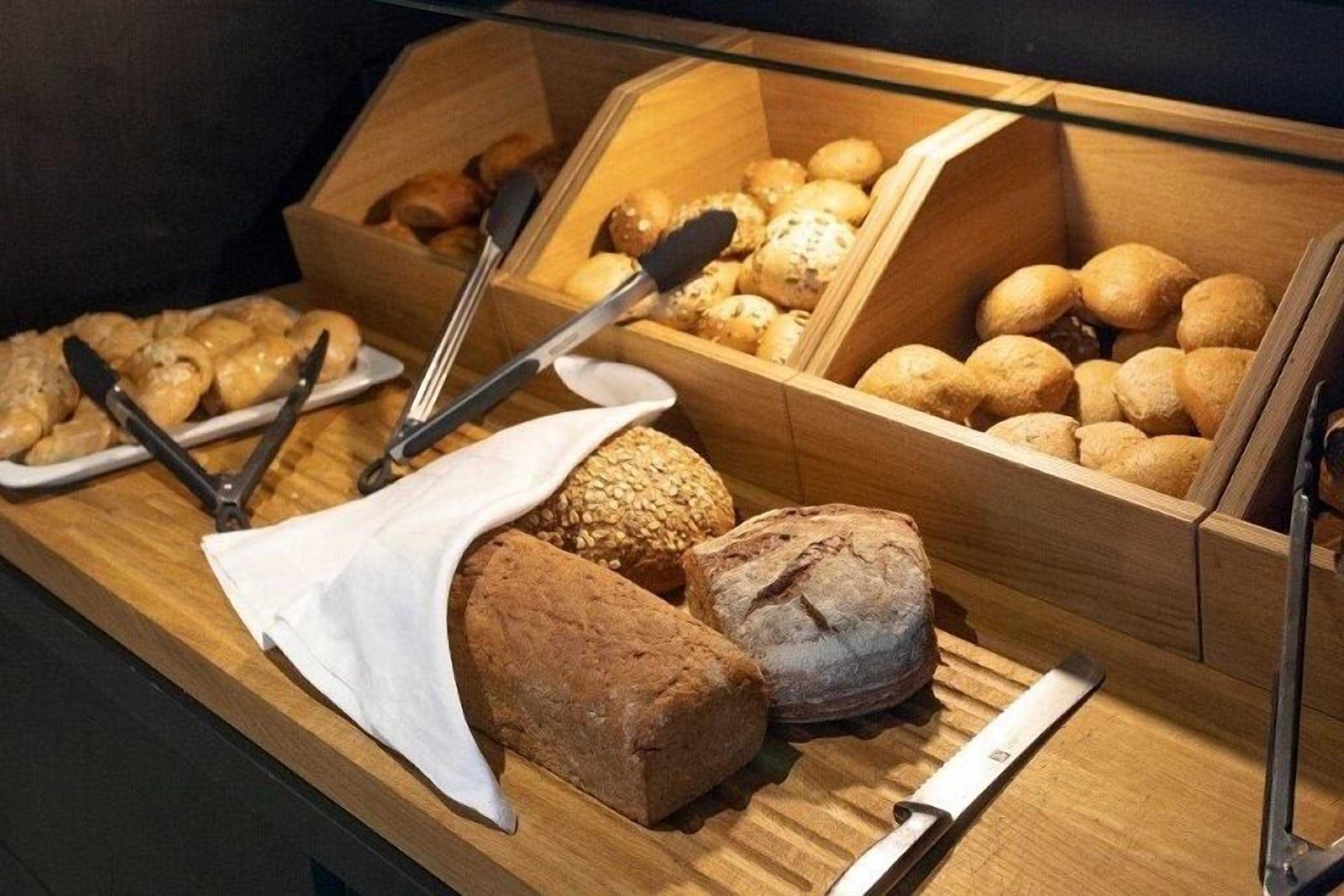 A display of various breads and pastries in wooden boxes.