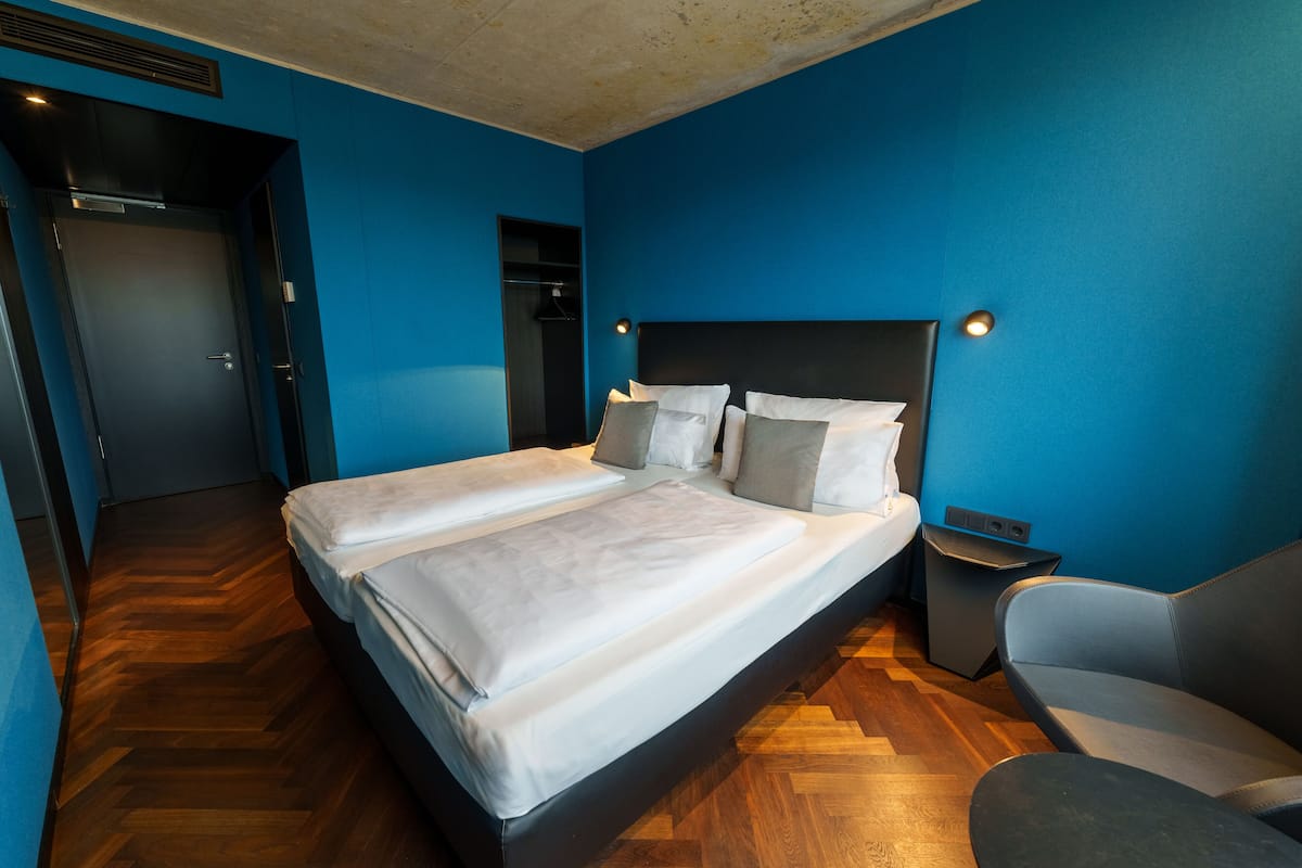 A hotel room with a large bed, a chair, and a small table.