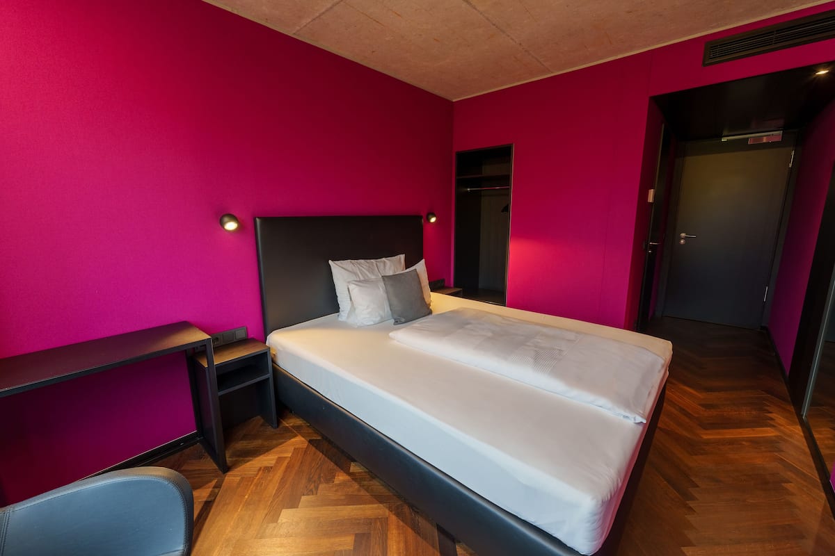 A modern bedroom with a bed, a desk, and a chair.