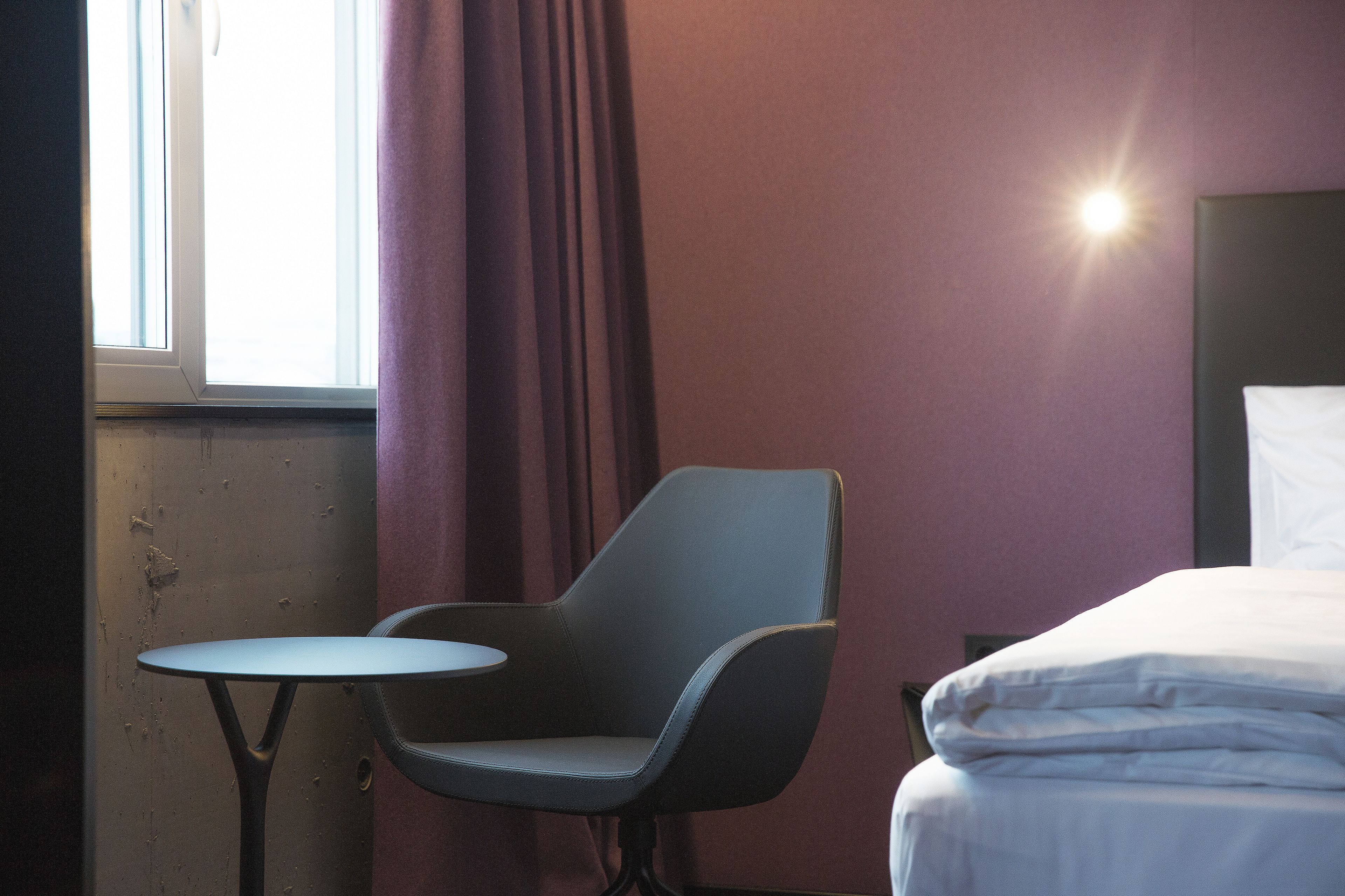 Una habitación de hotel con una cama, una silla y una mesita.