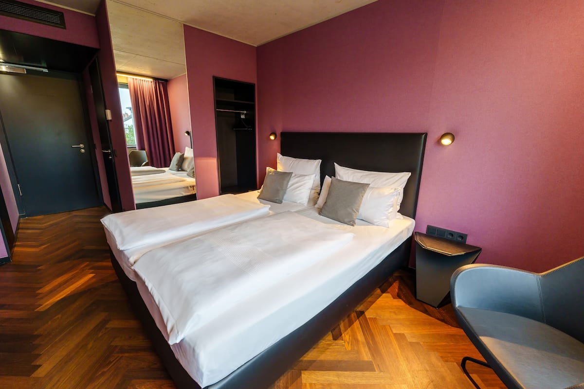 A hotel room with a large bed, a chair, and a small table.