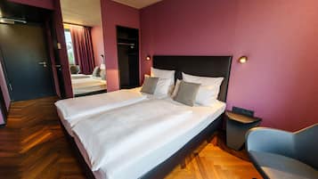 A hotel room with a large bed, a chair, and a small table.