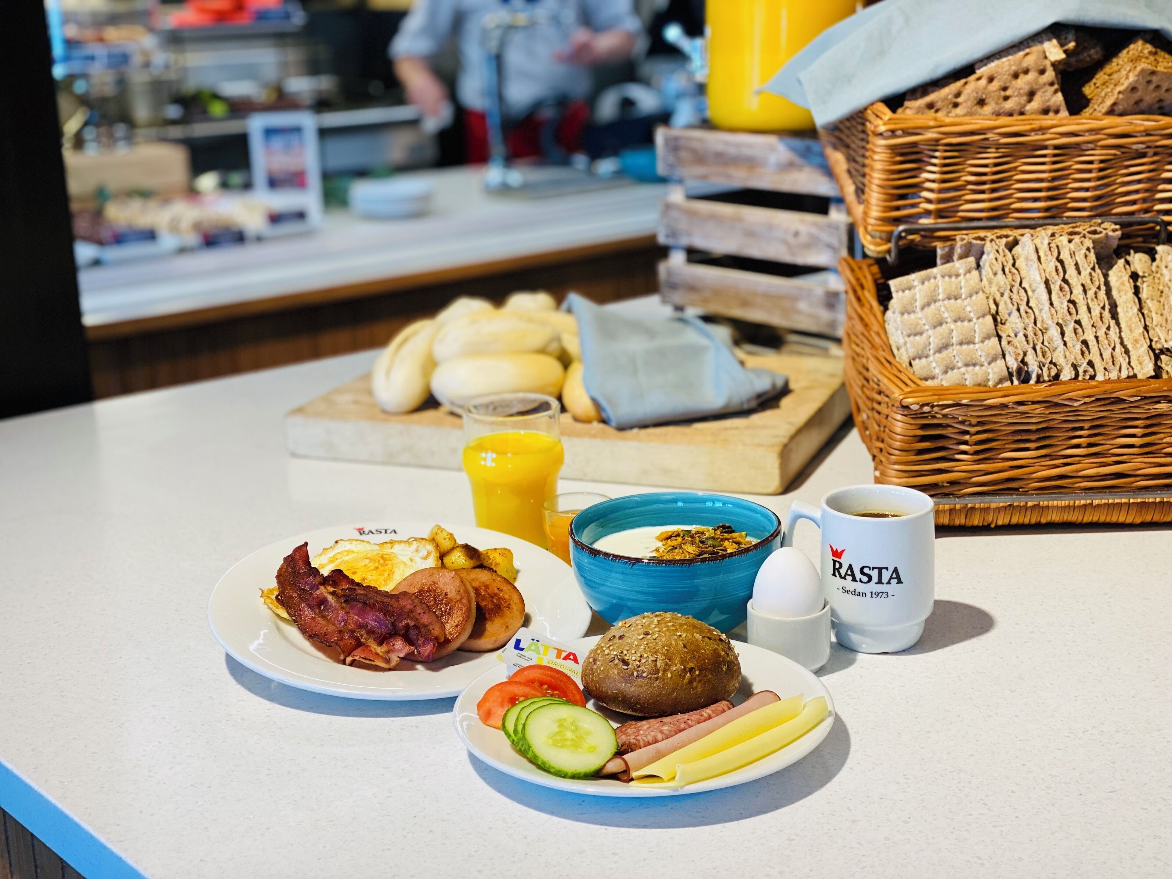 A breakfast table with plates of food, a coffee cup, and a basket of bread.